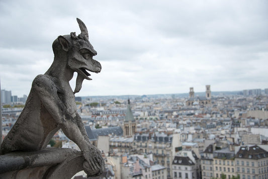 Gargoyle on top of a building overlooking a city.