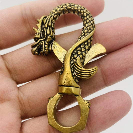 Brass dragon-shaped Keychain pendant held in a hand against a white background- Shadowplay Collection