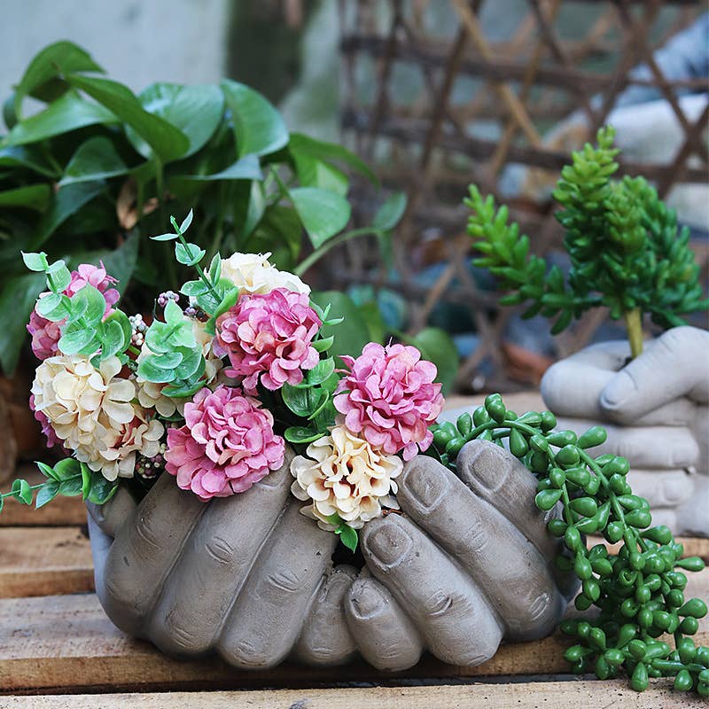 Ceramic hands holding flowers with greenery in the background- Shadowplay Collection Gift Shop