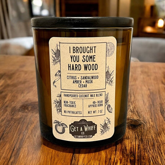 Glass candle with a label on a wooden surface- Shadowplay Collection Gift Shop