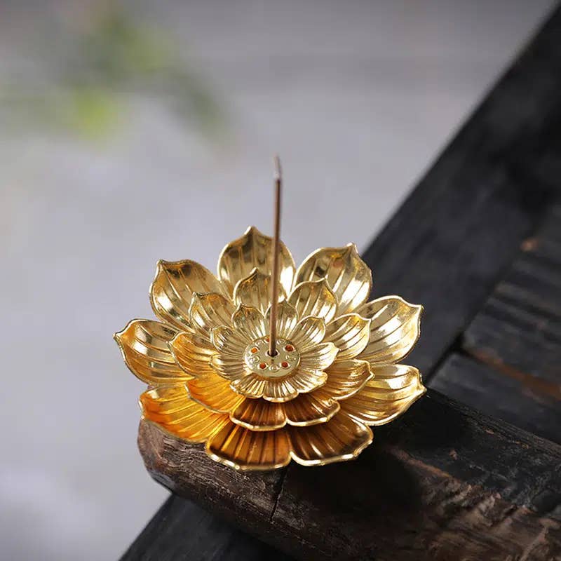 Gold lotus flower incense burner on a dark surface with a blurred background- Shadowplay Collection Gift Shop