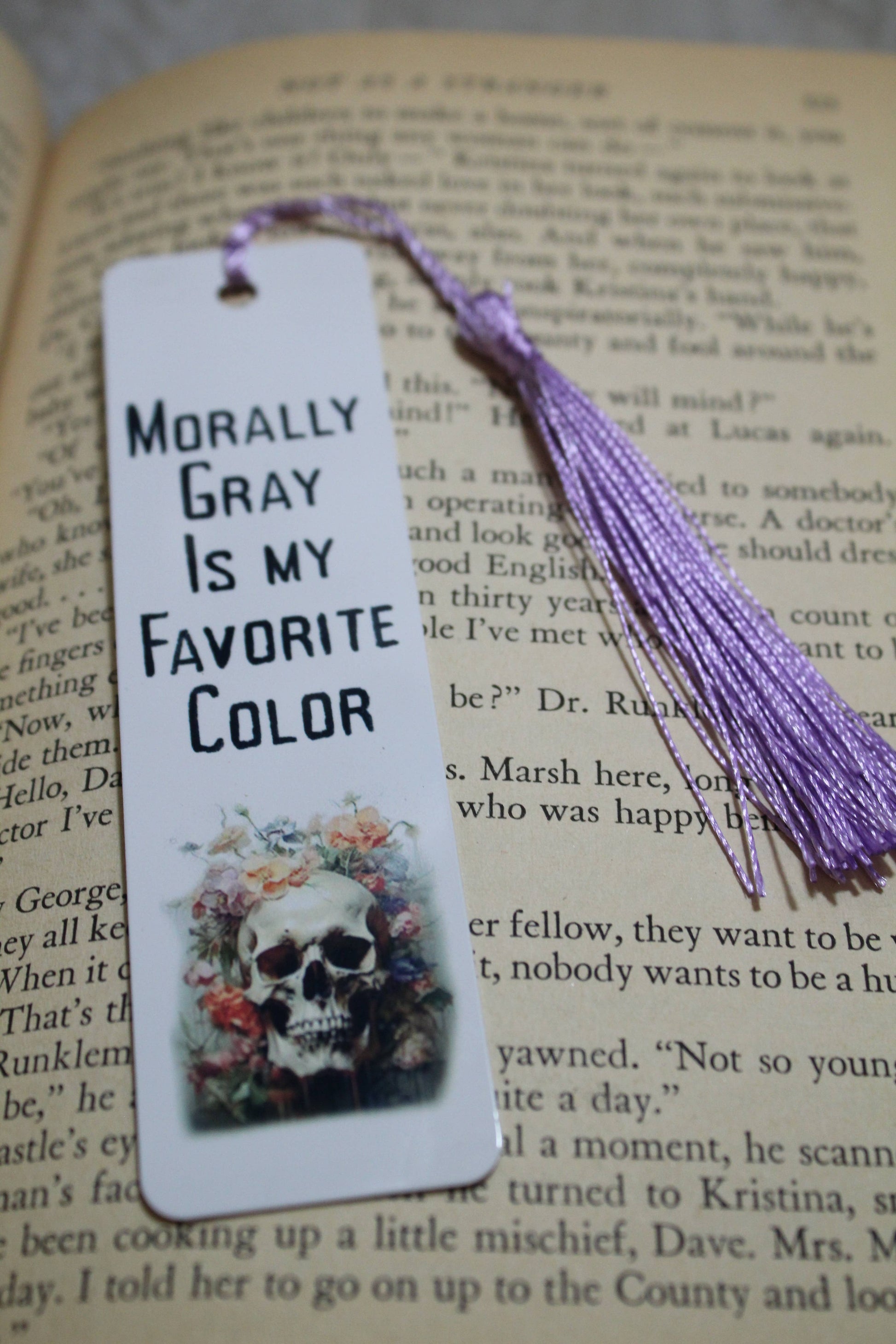 Bookmark with skull design and text 'Morally Gray Is My Favorite Color' on an open book.