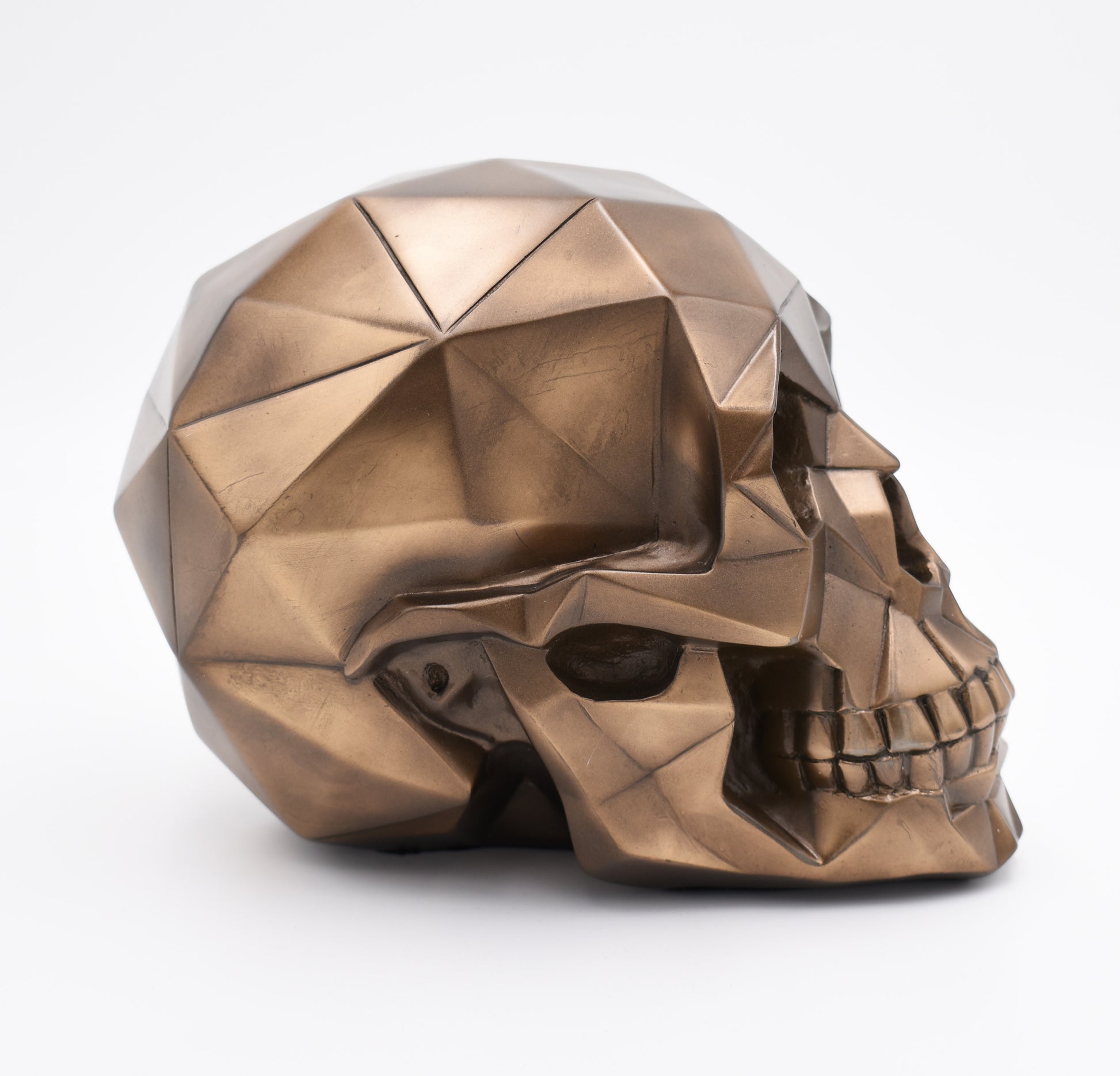 Bronze geometric skull sculpture on a white background