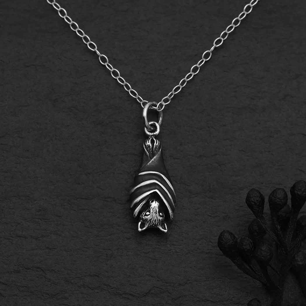 Silver necklace with a hanging bat on a dark textured background- Shadowplay Collection Gift Shop