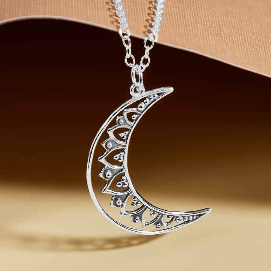 Silver crescent moon necklace on a brown background- Shadowplay Collection Gift Shop