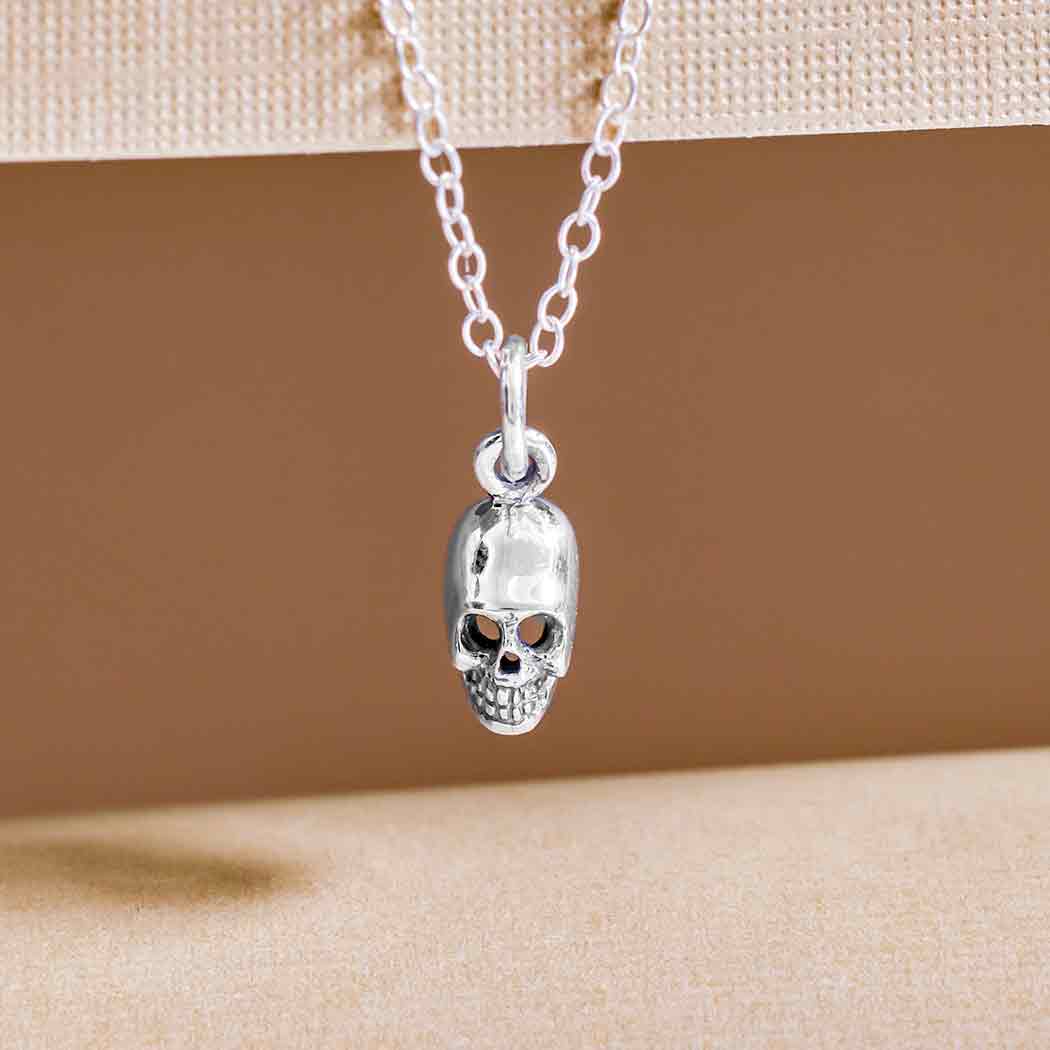 Silver skull pendant necklace on a beige background- Shadowplay Collection Gift Shop