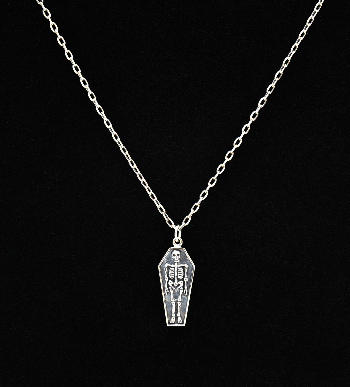 Silver necklace with a coffin pendant featuring a skeleton on a black background