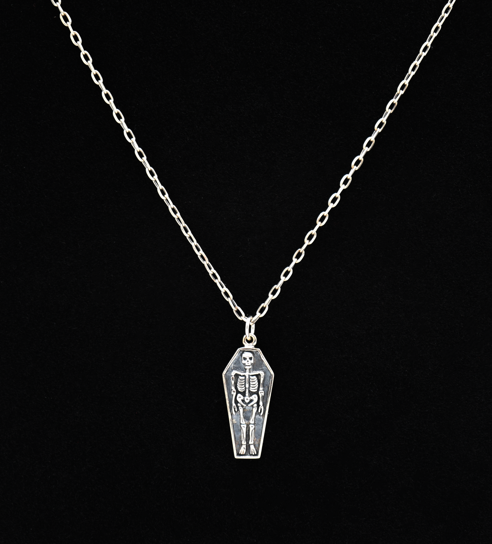 Silver necklace with a coffin pendant featuring a skeleton on a black background