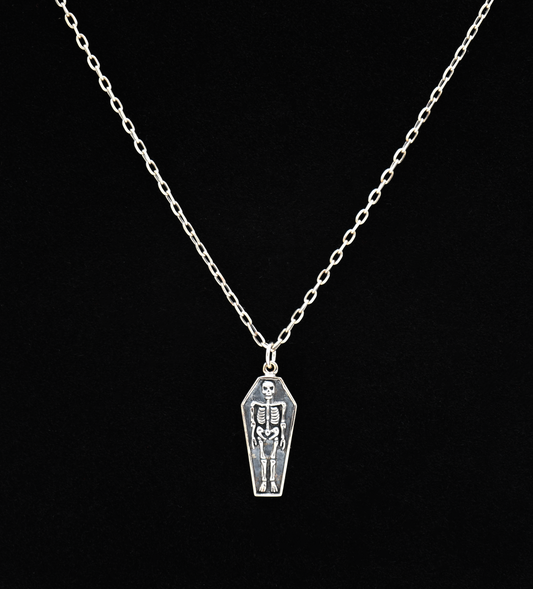 Silver necklace with a coffin pendant featuring a skeleton on a black background