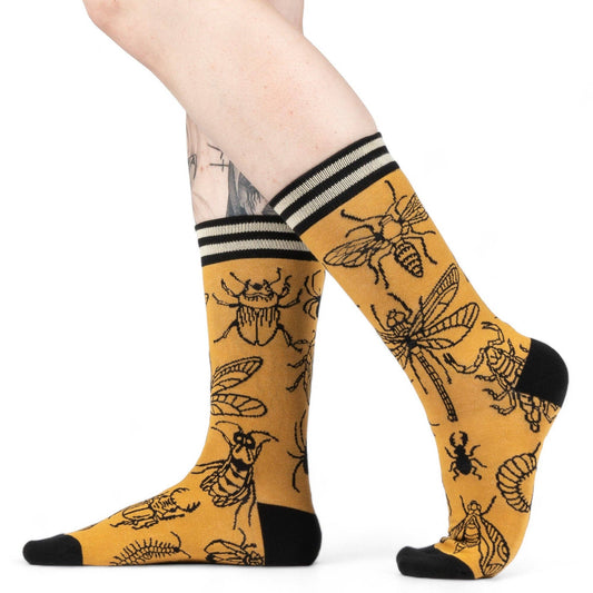 Yellow socks with black insect patterns worn by a person on a white background