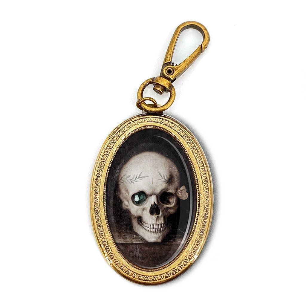 Gold-framed pendant with a skull design on a white background