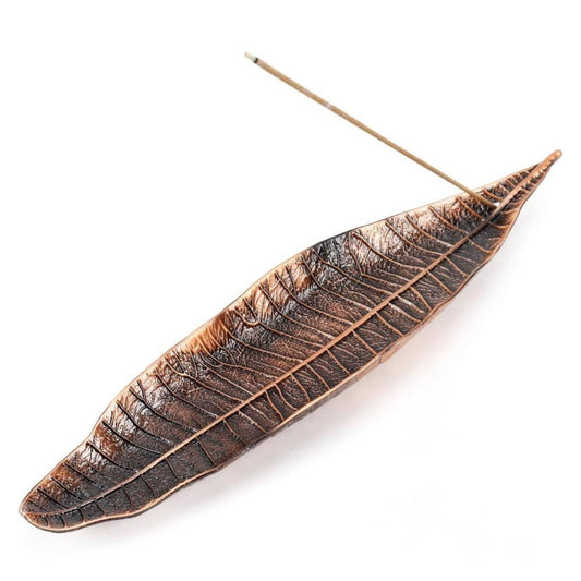 Decorative metal leaf-shaped incense holder with a n incense stick on a white background